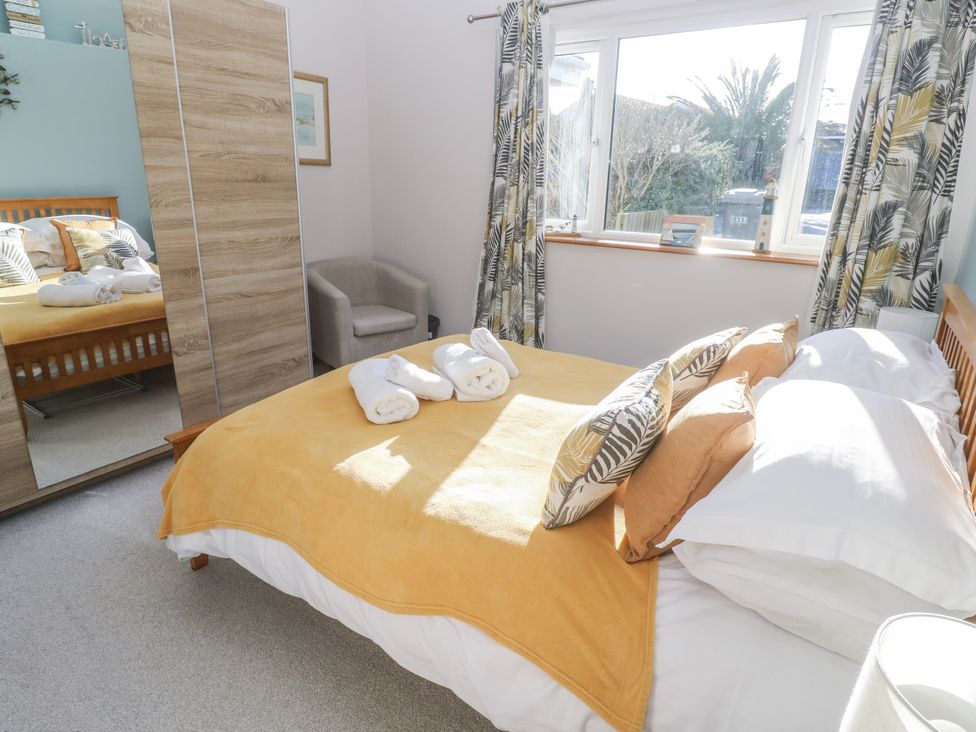A bedroom with a bed and a mirror at Blake Lodge in Crantock