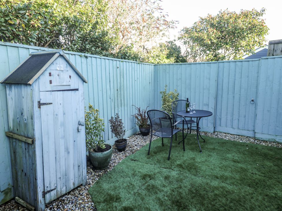 A garden with a table and chairs alongside a shed at Blake Lodge in Crantock