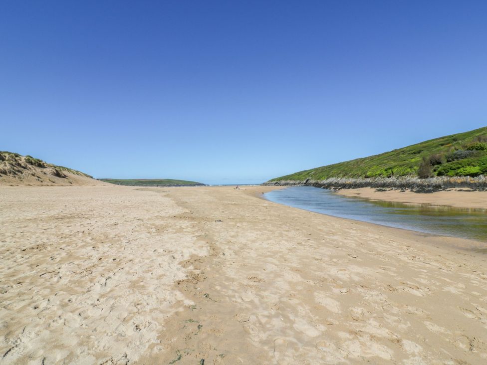 A sandy beach with hills and a river at Blake Lodge in Crantock