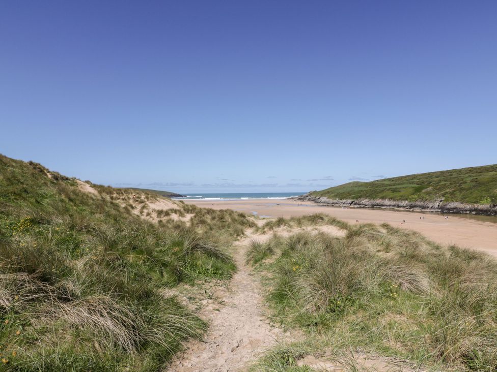 A beach with grass and a path leading to the sand at Blake Lodge in Crantock