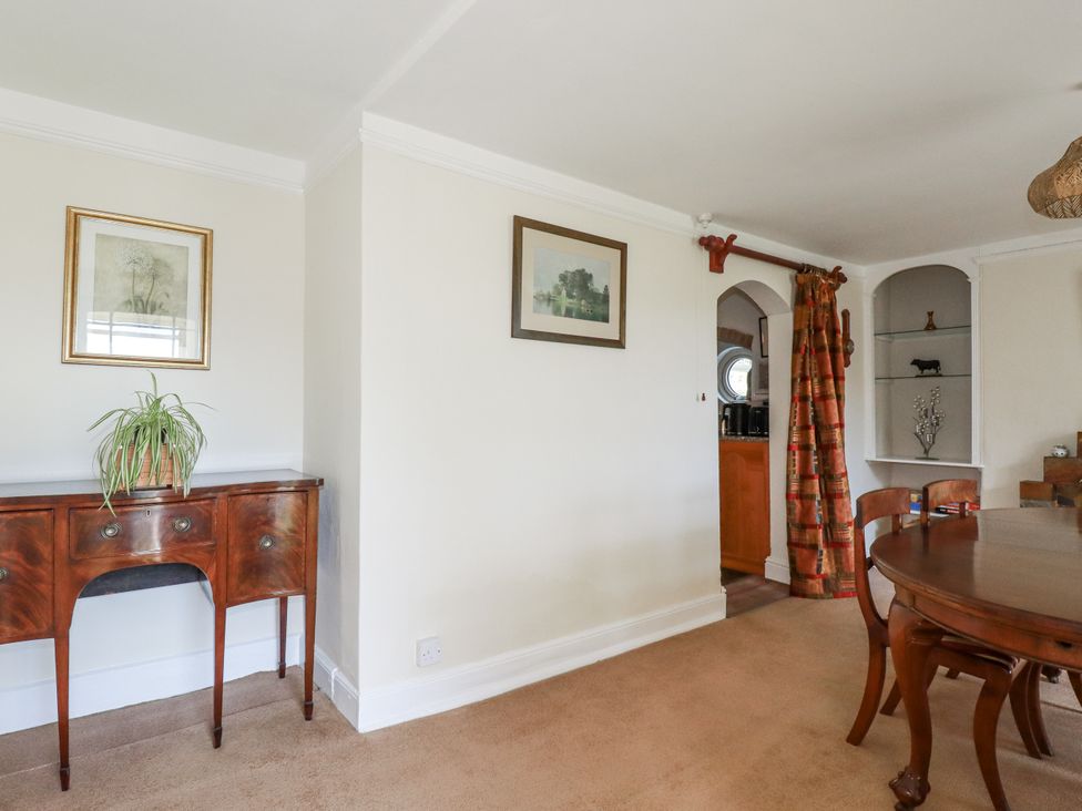 A dining room with a side table, framed artwork, and dining chairs at Tresarrett Manor in Bodmin