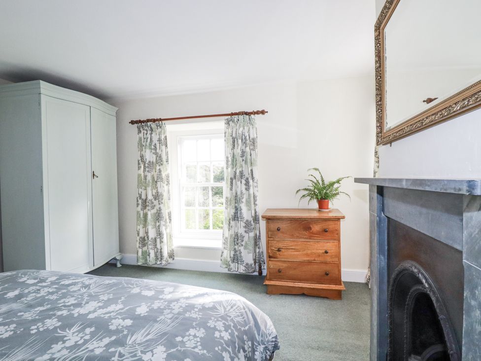 A bedroom with a wardrobe, chest of drawers, and window at Tresarrett Manor in Bodmin