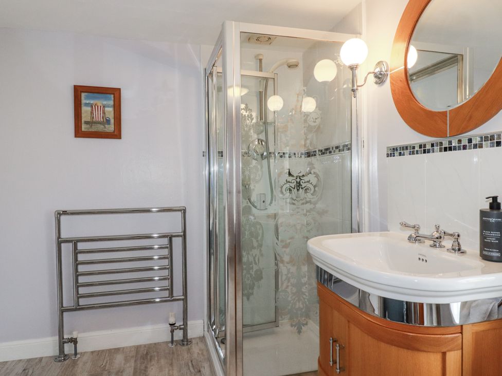 A bathroom featuring a shower, sink, towel rail, and a painting at Tresarrett Manor, Bodmin