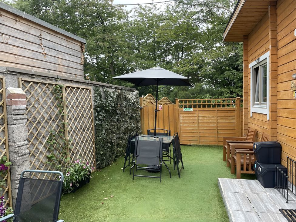 A garden with table and chairs under an umbrella at Duncairin cabins