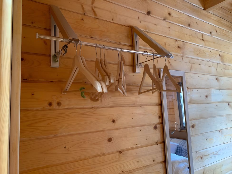 A rack with clothes hangers and a mirror in a bedroom at Duncairin cabins