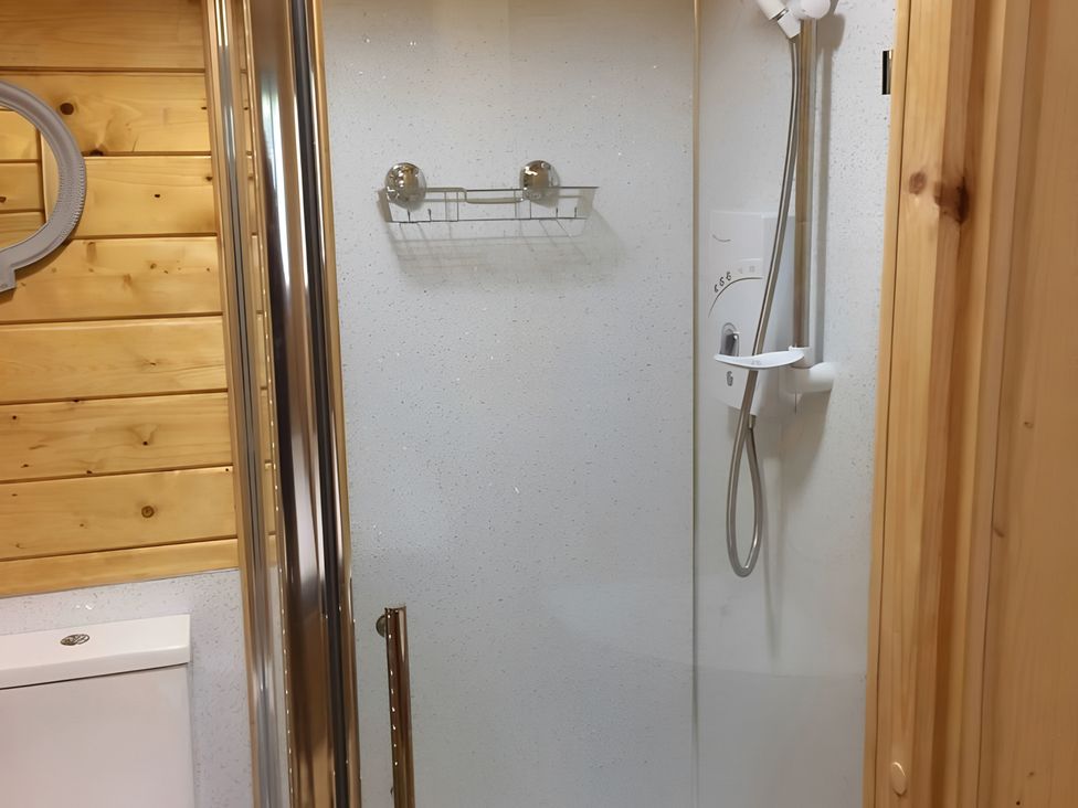 A shower with a showerhead and shelf in a bathroom at Duncairin cabins