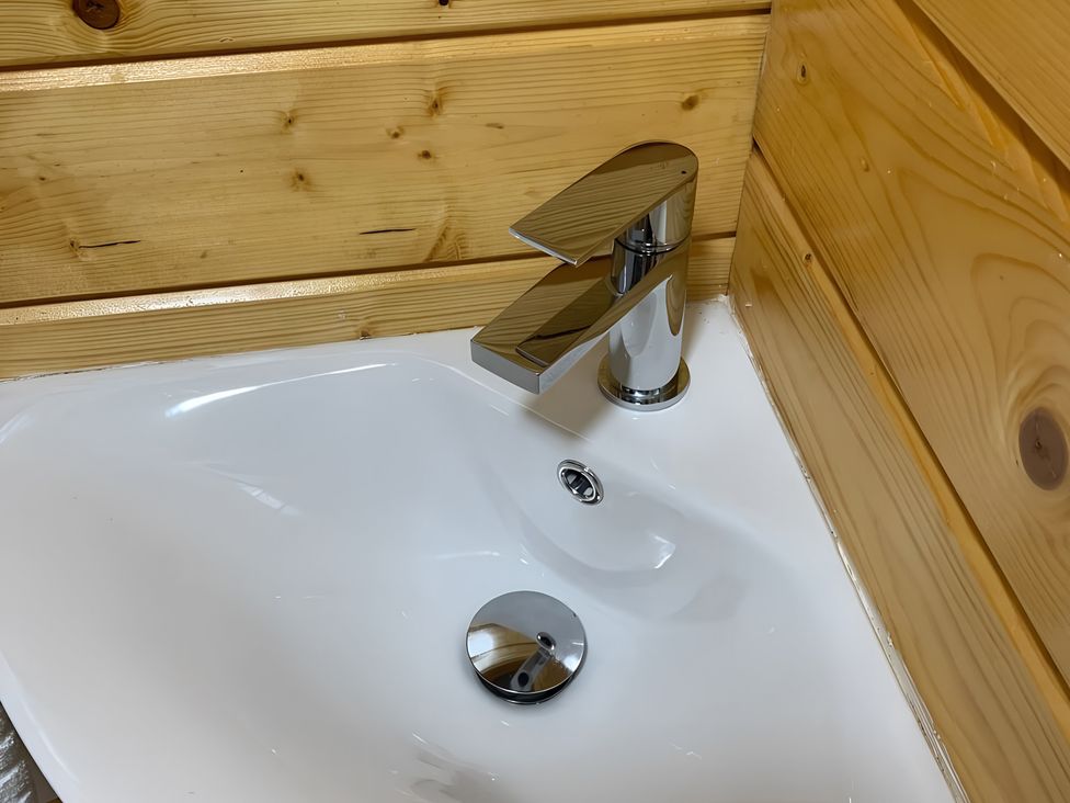 A sink with a faucet and wood paneling at Duncairin cabins