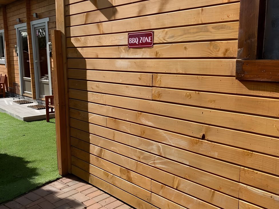 A wooden wall with BBQ zone sign at Duncairin cabins