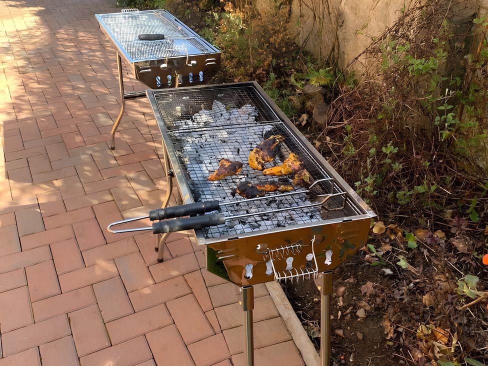 A grill with cooking meat in an outdoor area at Duncairin cabins