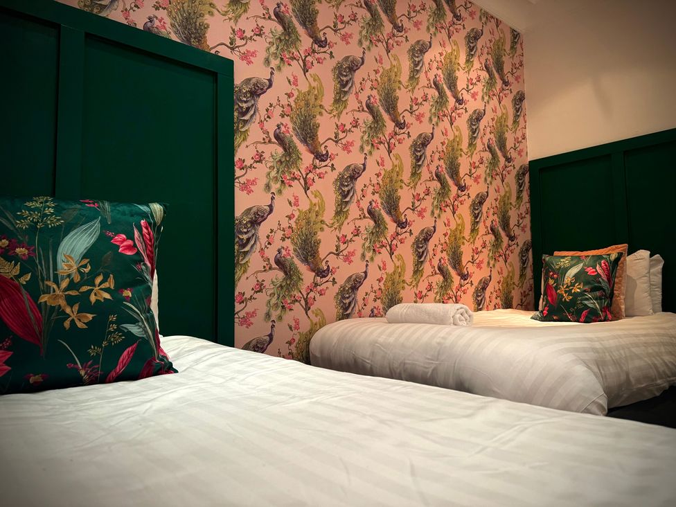 A bedroom with two beds and decorative wallpaper at Horncliffe Hot Tub House