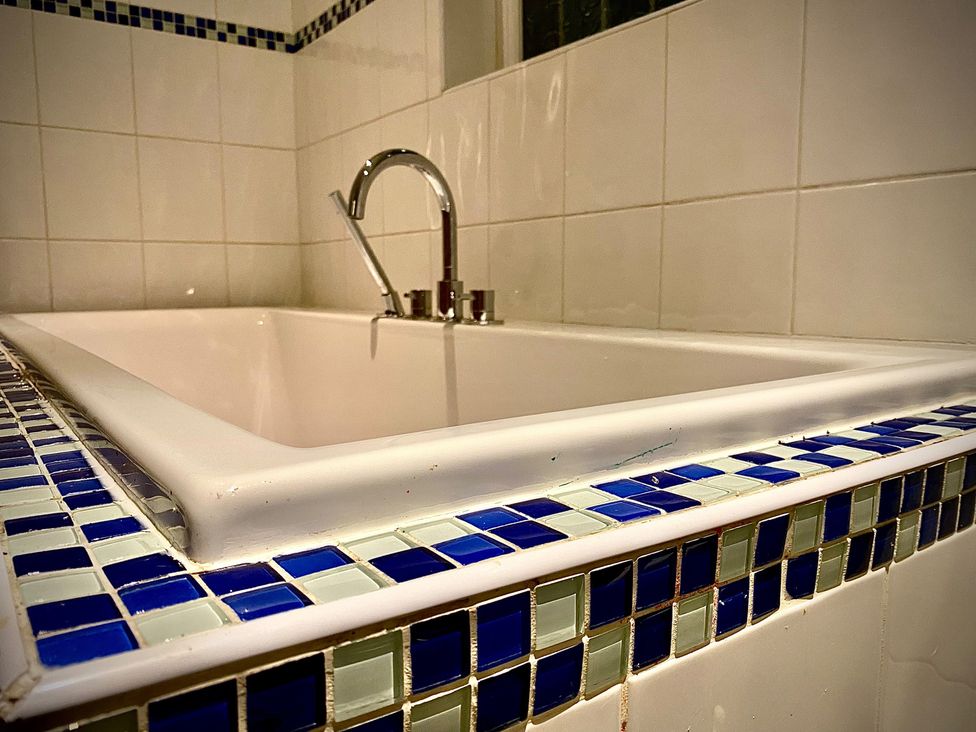 A bathtub with a faucet and tiled wall at Horncliffe Hot Tub House