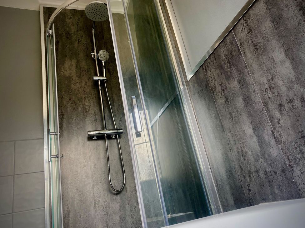 A shower with a glass door and showerhead at Horncliffe Hot Tub House