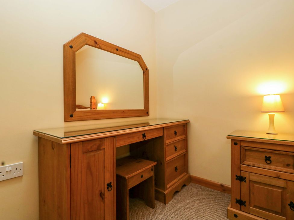 A bedroom with a dressing table and lamp at Orchard Cottage in Corse near Gloucester