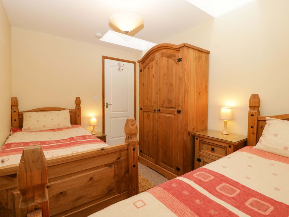 A bedroom with two beds and wooden furniture at Orchard Cottage in Corse near Gloucester