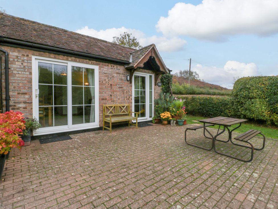 An outdoor patio area with a table and bench at Orchard Cottage in Corse near Gloucester