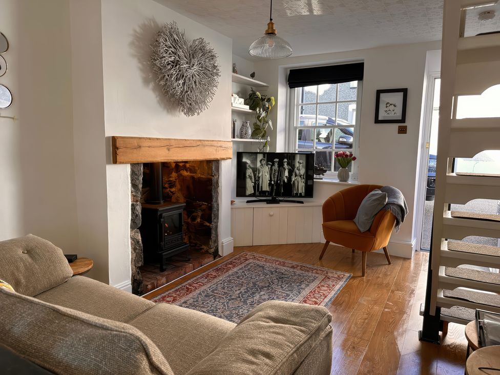 A living room with a sofa, television and fireplace at Periwinkle Cottage in Conwy