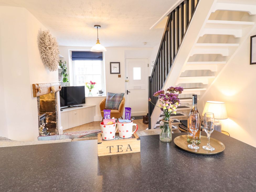 A living room with a TV, chairs, and a table at Periwinkle Cottage in Conwy