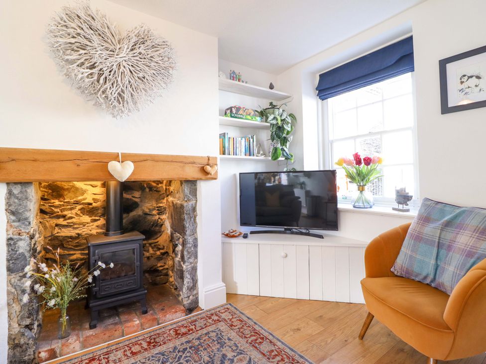 A living room with a fireplace and a television at Periwinkle Cottage in Conwy