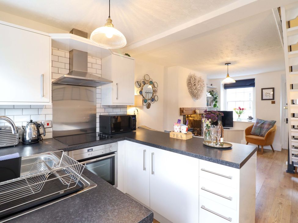 A kitchen with appliances and seating area at Periwinkle Cottage in Conwy
