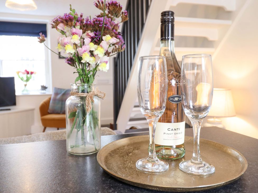 A living room with a tray, wine glasses, and flowers at Periwinkle Cottage, Conwy