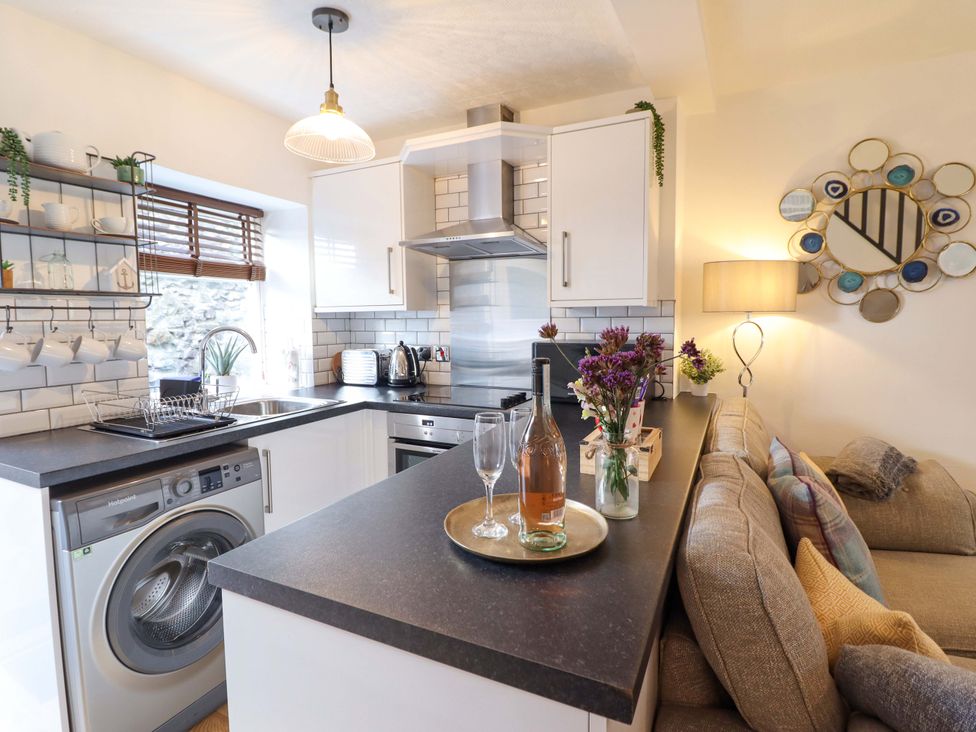 A kitchen with a washing machine and stove at Periwinkle Cottage, Conwy