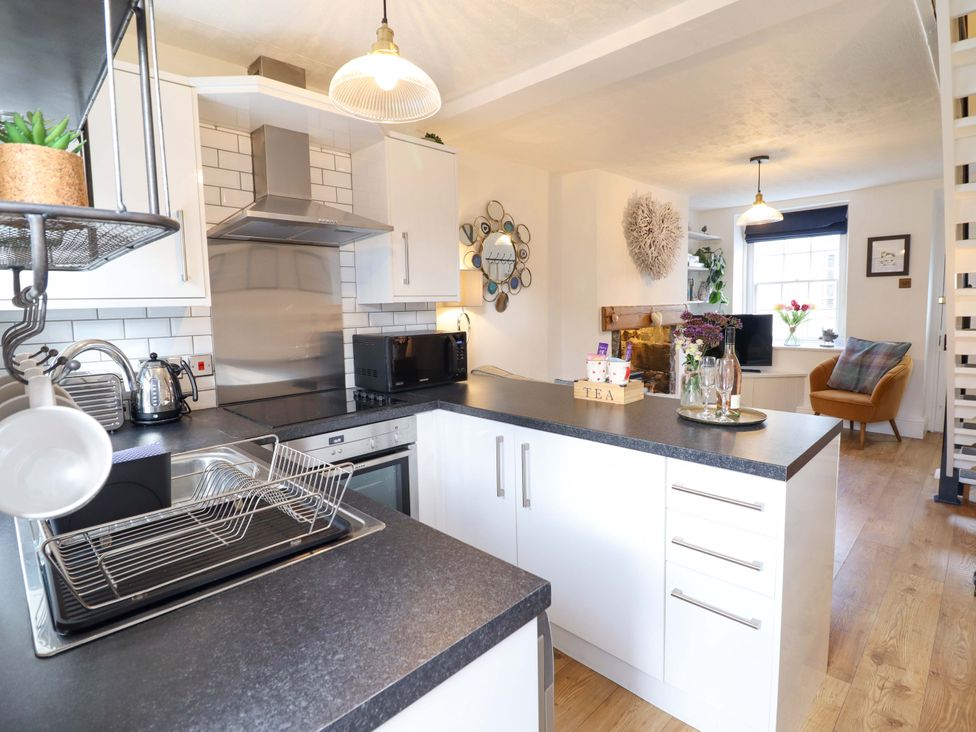 A kitchen with appliances and seating area at Periwinkle Cottage in Conwy
