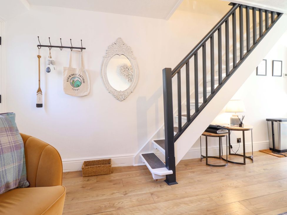 A hallway with a staircase and a coat rack at Periwinkle Cottage Conwy