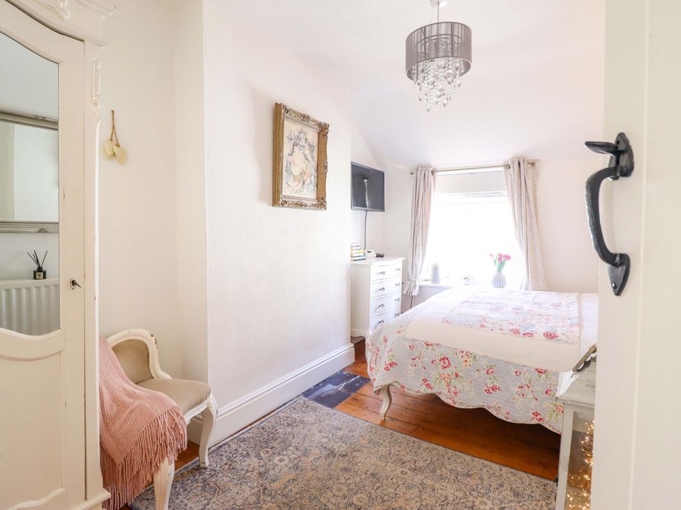 A bedroom with a bed and dresser at Periwinkle Cottage in Conwy
