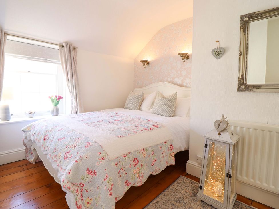 A bedroom with a bed, window, and lamp at Periwinkle Cottage in Conwy