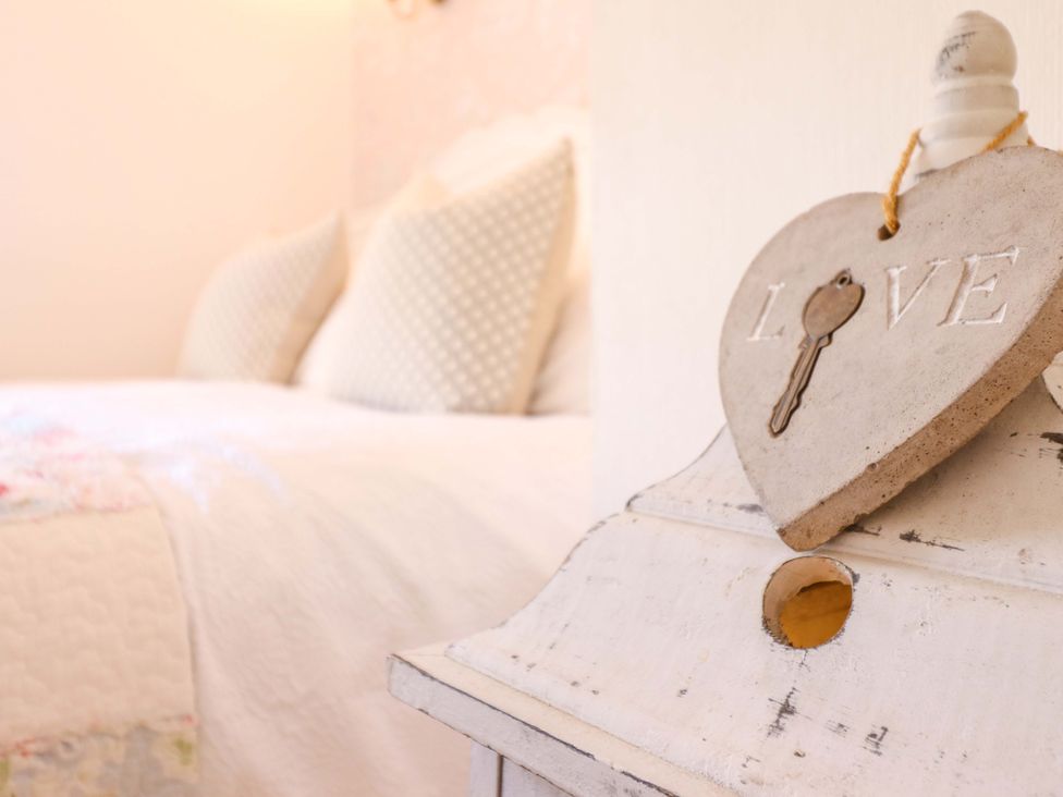 A bedroom with a heart-shaped love sign and a bed at Periwinkle Cottage in Conwy