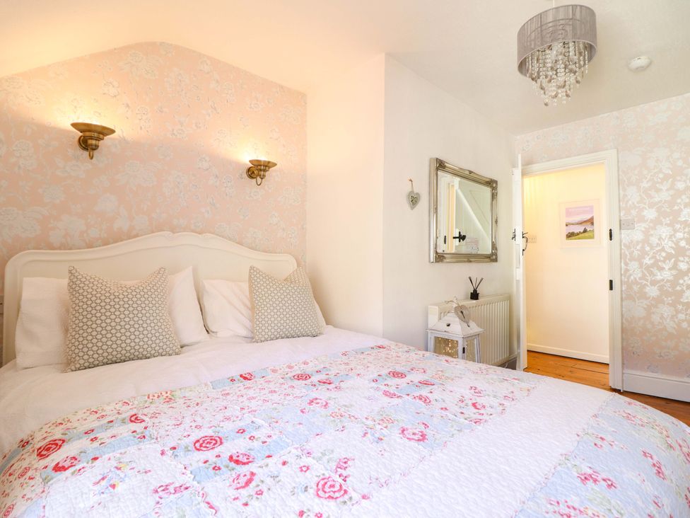 A bedroom with a bed and mirror at Periwinkle Cottage in Conwy