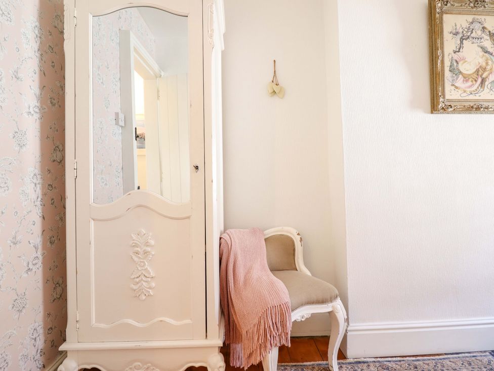 A wardrobe and small chair in a hallway at Periwinkle Cottage in Conwy