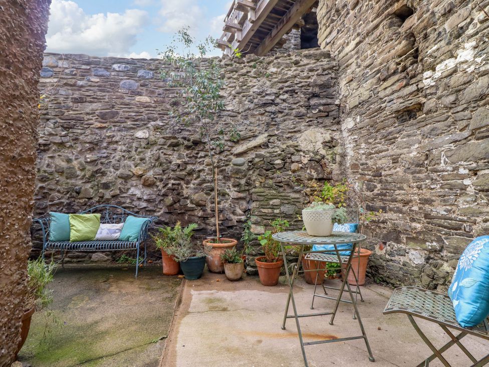 A garden area with a stone wall and seating at Periwinkle Cottage in Conwy
