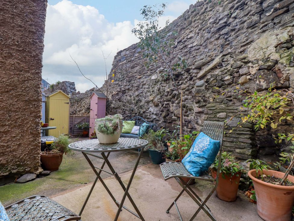 A garden with a table and chairs surrounded by plants at Periwinkle Cottage in Conwy