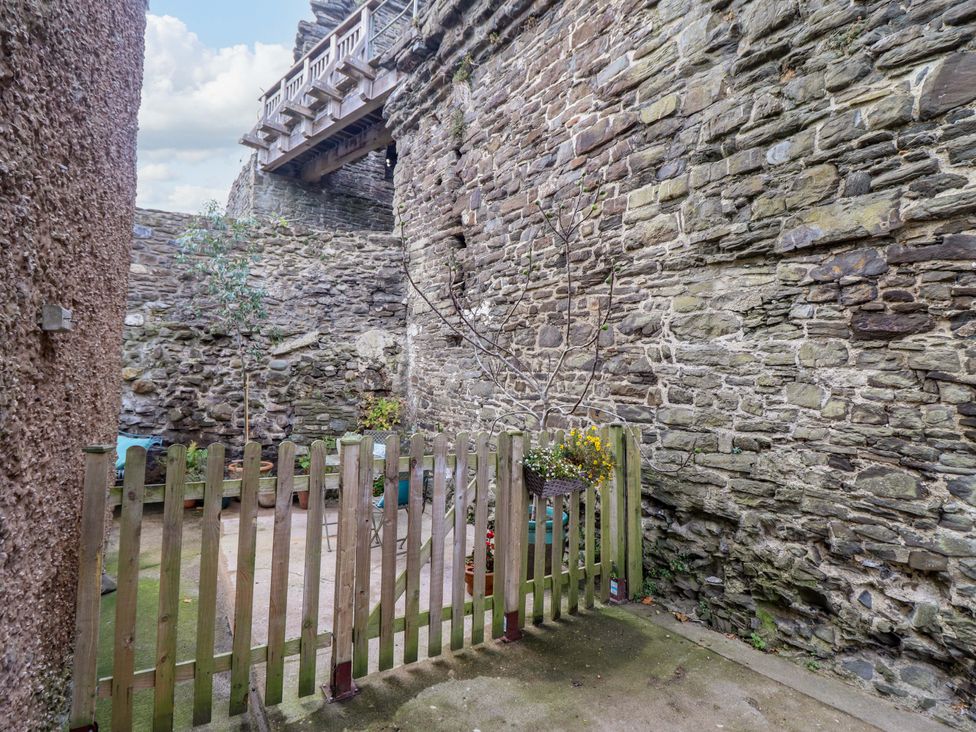 A garden area with a fence and stone walls at Periwinkle Cottage in Conwy