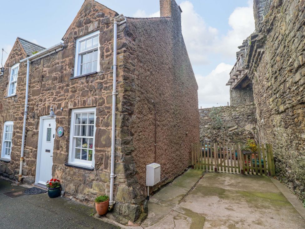 An exterior view of a cottage with stone walls and a garden area at Periwinkle Cottage in Conwy