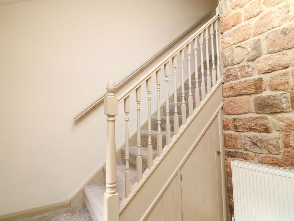 A staircase with a stone wall and a radiator at The Annex in Belper