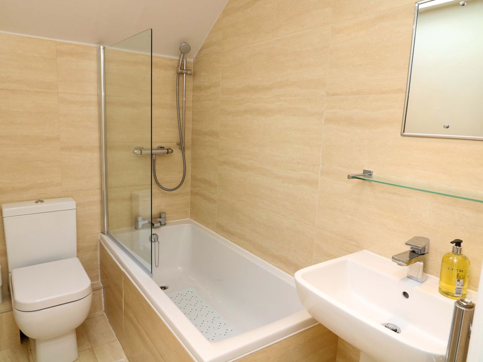 A bathroom with a toilet, bathtub, sink, and mirror at The Annex in Belper