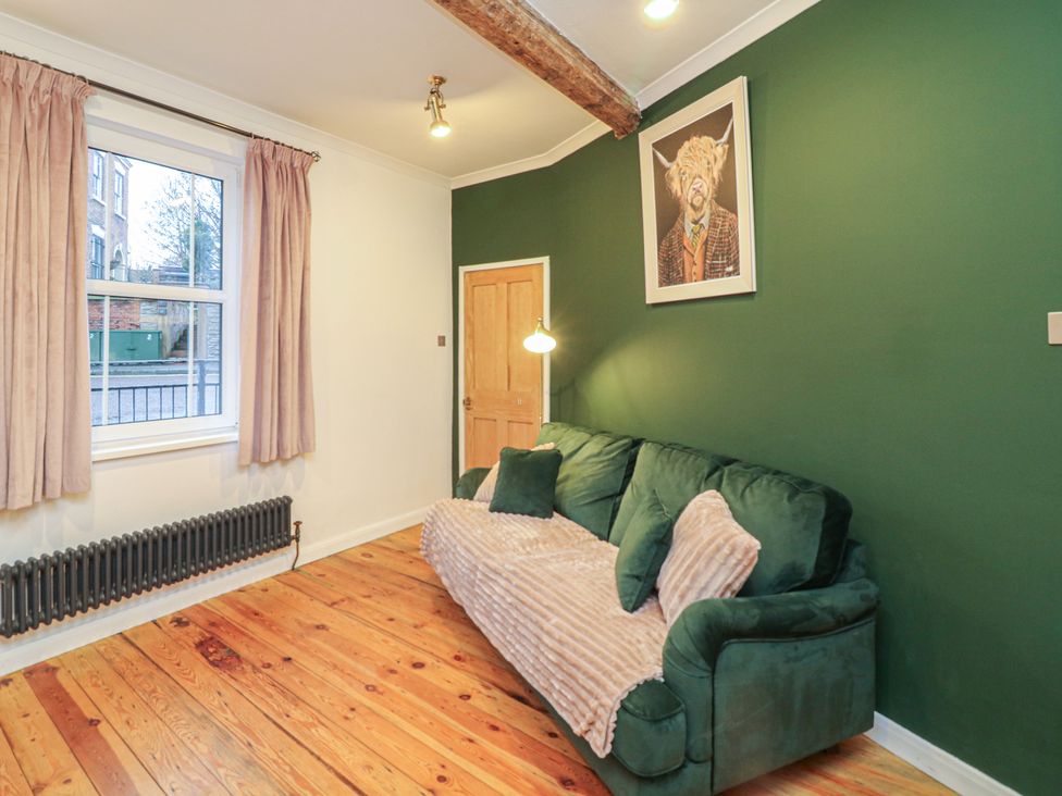 A living room with a green wall and sofa at 1 Nottingham Road in Southwell