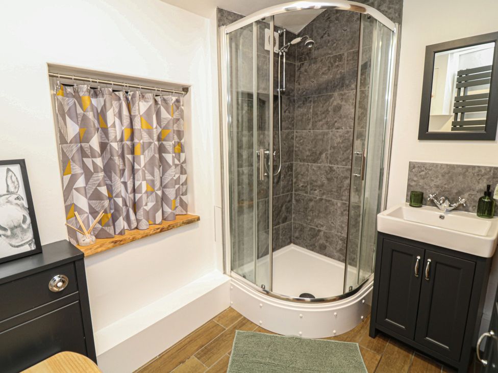 A bathroom with a shower, sink, curtain, and mirror at 1 Nottingham Road in Southwell