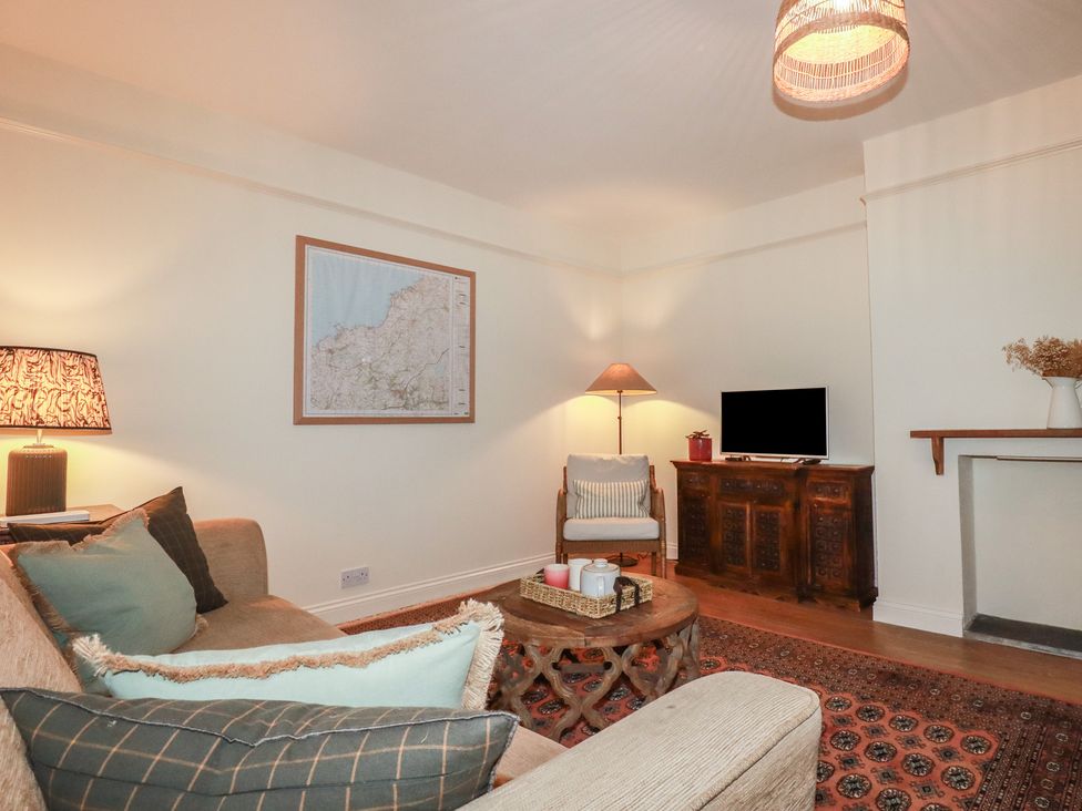 A living room with a sofa, lamp, and television at Copper Mine Cottage in Bodmin