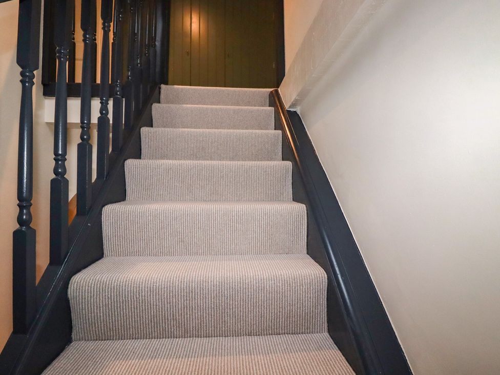 A staircase with carpet and a door at Copper Mine Cottage in Bodmin