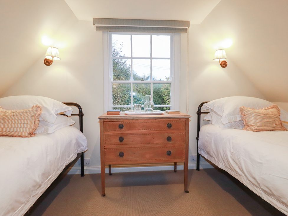A bedroom with two beds and a cabinet at Copper Mine Cottage in Bodmin