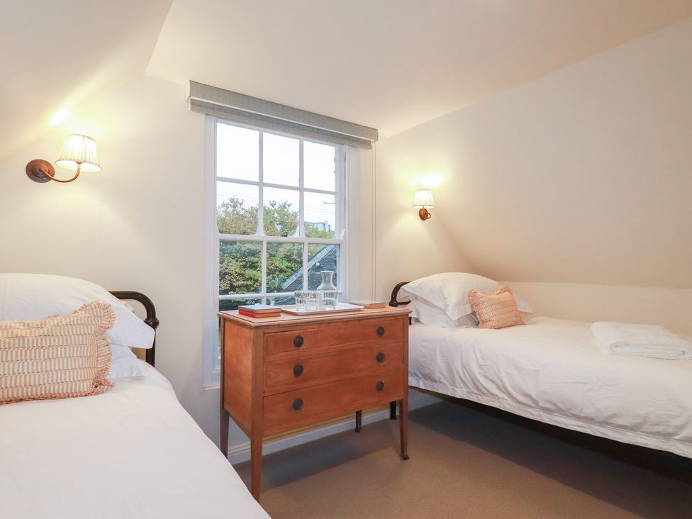 A bedroom with two beds and a nightstand at Copper Mine Cottage in Bodmin