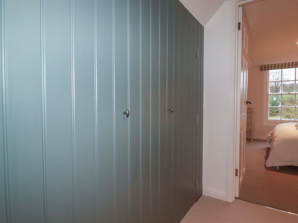 A bedroom with a blue wall and a door leading to another room at Copper Mine Cottage in Bodmin