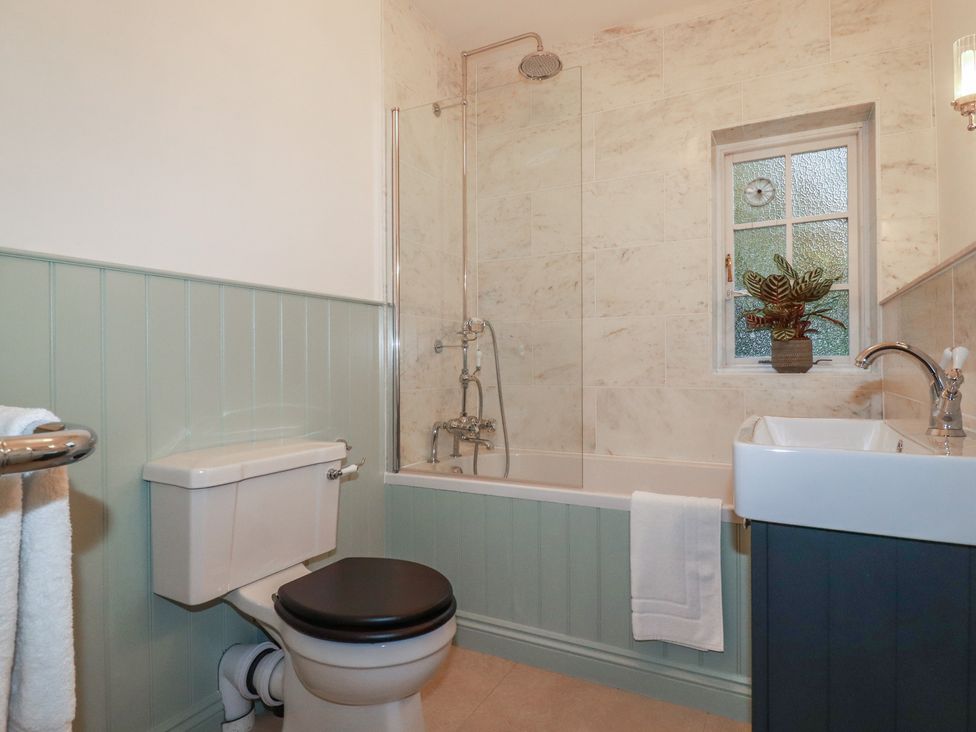 A bathroom with a shower above a bath and a sink at Copper Mine Cottage in Bodmin