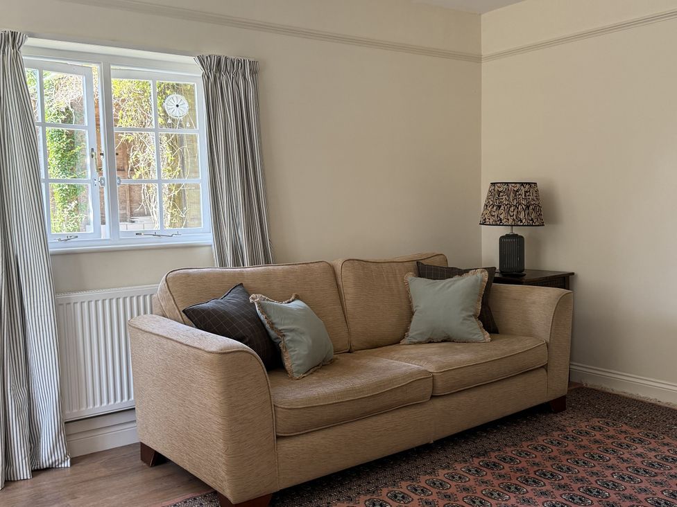 A living room with a sofa lamp and window at Copper Mine Cottage Trelill near Port Isaac