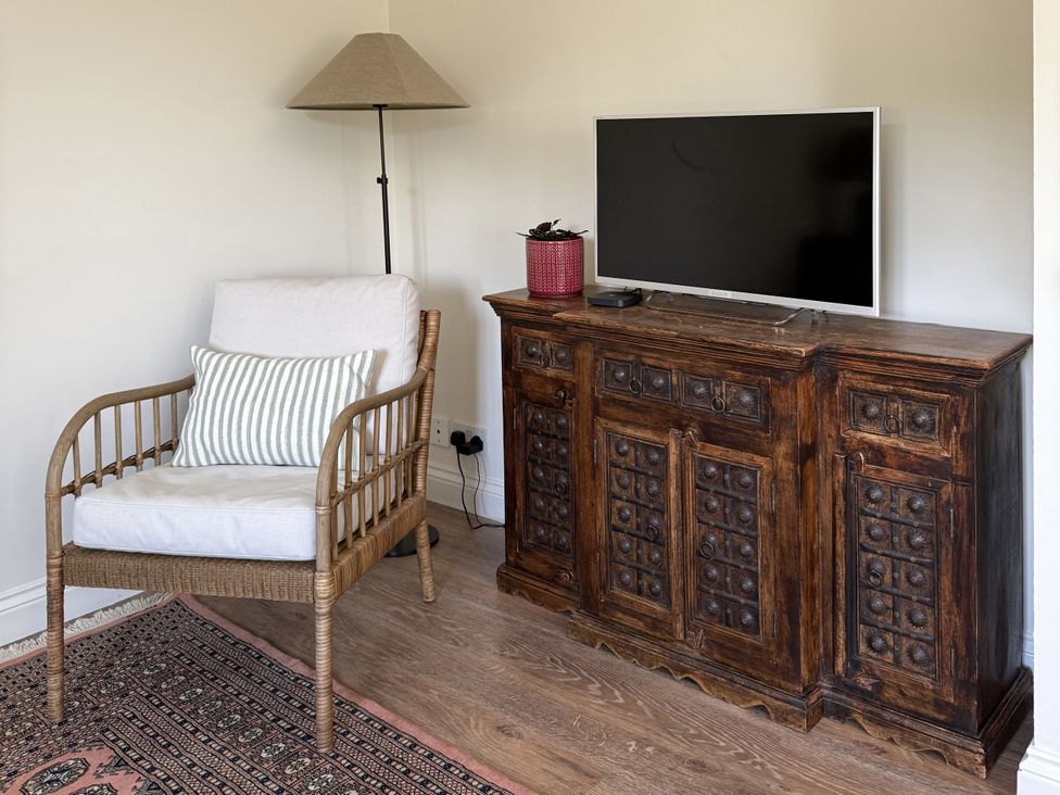 A living room with an armchair and television at Copper Mine Cottage in Trelill near Port Isaac