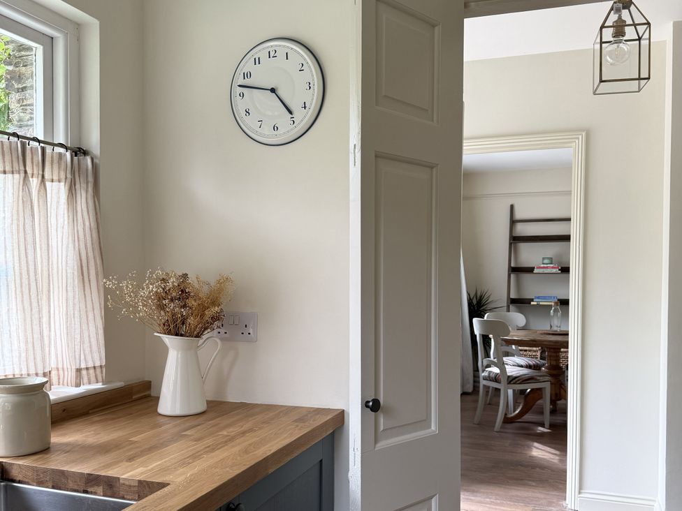 A kitchen with a clock and a door to another room at Copper Mine Cottage Trelill near Port Isaac