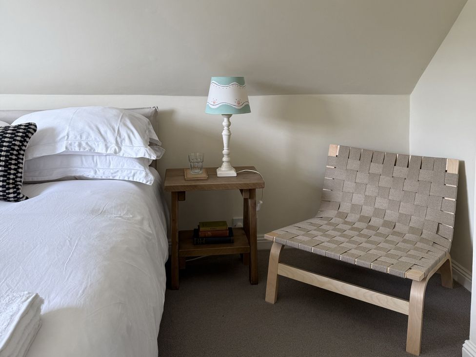 A bedroom with a bed, nightstand, lamp and chair at Copper Mine Cottage Trelill near Port Isaac